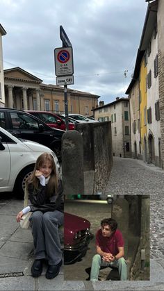 two people are sitting on the curb next to parked cars