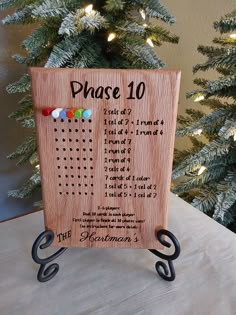 a wooden plaque with the words phase 10 written on it next to a christmas tree