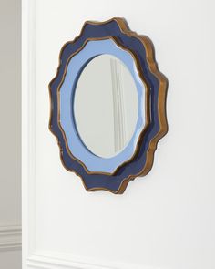 a round mirror mounted to the side of a white wall next to a doorway and door