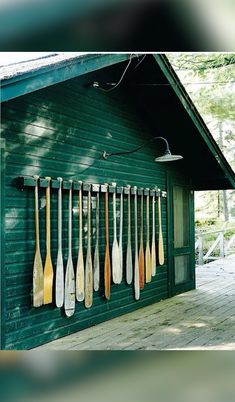 there are many paddles hanging on the side of this building and it is green