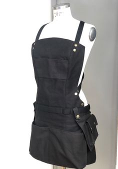 a mannequin wearing a black dress with buttons on the back and straps at the waist