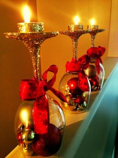 two glass vases filled with ornaments and lit candles on top of a shelf next to each other