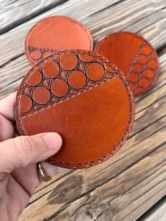 someone is holding two leather coasters in their hand