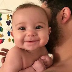 a man holding a baby in his arms and looking at the camera with an excited look on his face