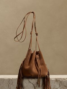 We updated our best-selling bucket bag, adding fringed leather accents and increasing storage space to accommodate even the largest phones.  Handcrafted in Italy of Italian suede.  Drawstring closure.  Adjustable shoulder strap.  Height: 7" (18cm) Diameter: 7" (18cm) Strap drop: 25" (38cm) Leather Fringe Bag, Fringe Handbags, Inspired Handbags, Fall Bags, Fringe Purse, Fringe Bags, Boho Leather, Leather Accents, Western Wedding