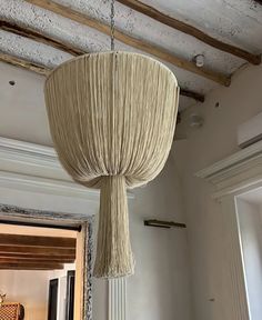 a light fixture hanging from the ceiling in a room with white walls and wood beams