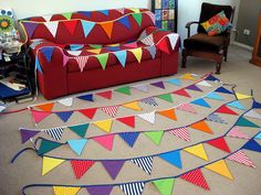 a living room with a red couch and colorful flags on the floor in front of it