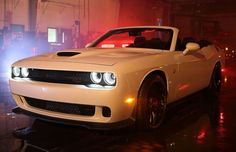 a white sports car parked in a garage with its lights on and the hood up