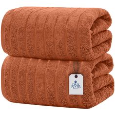 two orange towels stacked on top of each other with a tag hanging from the front