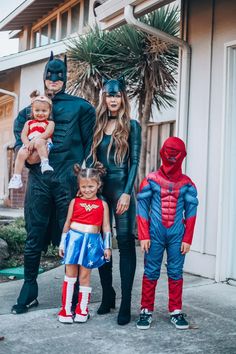 the family is dressed up as superheros and their children are standing in front of a house