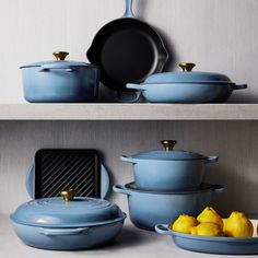 blue pots and pans on shelves with lemons in the foreground, and an empty cast iron skillet behind them