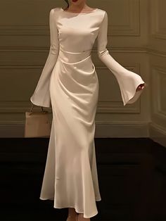 Experience the jazz-age revival with this elegantly designed white gown, complete with bell sleeves that add a vintage touch to a modern silhouette. The sleek bodice highlights the natural waistline, while the gently flaring skirt creates a flowing movement as you walk. Made from premium fabric that hugs the body while allowing for a full range of motion, this dress combines the best of both comfort and style. It’s a contemporary take on classic glamour, perfect for evenings where making a grace White Sleeved Dress, Satin White Dress With Sleeves, Bell Sleeve Dresses, How To Style Simple Dress, White Dresses With Sleeves, Modern Dress Designs, Dresses With Flared Sleeves, Marriage Dresses For Women, Soiree Dress Short