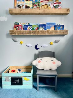 two wooden shelves with books on them above a child's chair and toy chest