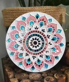 a white plate with pink and blue designs on it sitting on top of wood logs