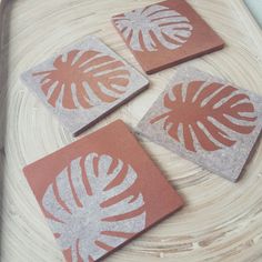 four coasters with orange and white designs on them sitting on a table top next to each other