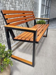 a wooden bench sitting in front of a brick wall next to a potted plant