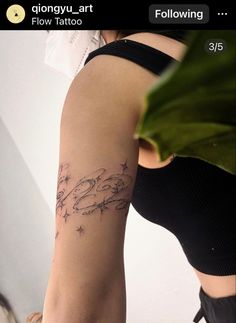 a woman with a tattoo on her arm is looking down at the ground while holding a plant