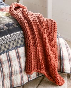 an orange knitted blanket on top of a bed