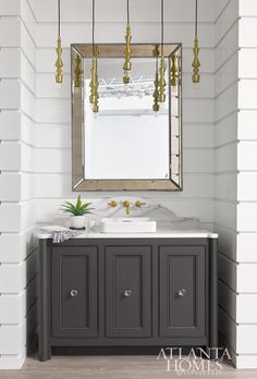 a bathroom vanity with a mirror above it and lights hanging from the ceiling over it