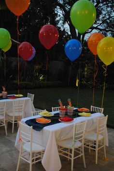 an outdoor party with balloons and plates on the table