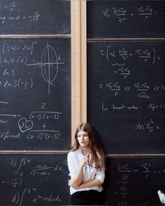 a young woman standing in front of a blackboard