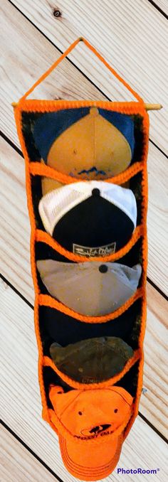 several hats in an orange holder on a wooden surface