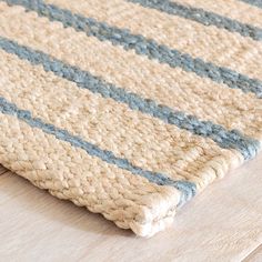 a close up of a rug on a wooden floor with blue and white stripes in the middle