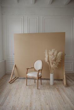 a chair and vase sitting in front of a wall with white paint on it's walls