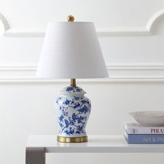 a blue and white vase sitting on top of a table next to a lamp