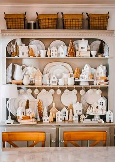 a china cabinet filled with white dishes and christmas decorations on top of wooden shelves in a kitchen