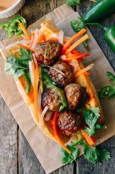 a sandwich with meatballs, carrots and lettuce on a piece of paper