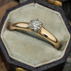 an engagement ring with a diamond sits in a velvet box on top of other jewelry