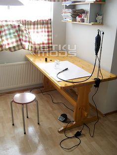 a room with a wooden table and some wires on the desk next to a window