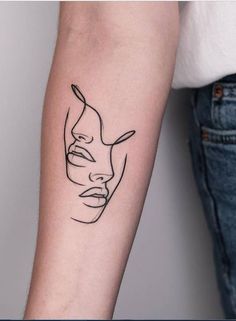 a woman's arm with a black line drawing of a face on the left forearm