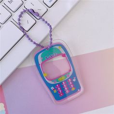 a pink and blue cell phone keychain sitting on top of a keyboard