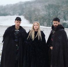 two men and a woman dressed in black standing next to each other on snow covered ground