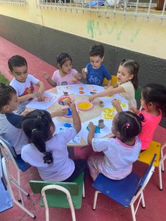 a group of children sitting around a table painting