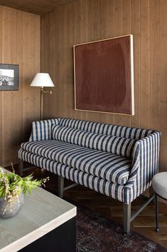 a striped couch and chair in a living room with wood paneling on the walls