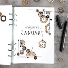 an open planner with gears on it next to some pens and other items that are scattered around