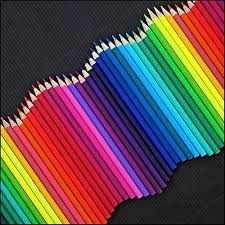 many colored pencils are lined up on a black surface