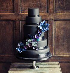 three different cakes with flowers on top and bottom, one is black the other is white