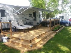 a mobile home with deck and chairs in the grass