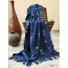 a blue and white blanket sitting on top of a wooden bench next to a vase