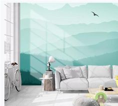 a living room with a white couch and green mountains on the wall, along with a bird flying in the sky