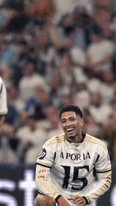 a soccer player sitting on the ground in front of a crowd with his mouth open