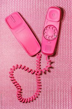 an old pink phone laying on top of a pink table next to it's cord