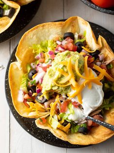 two black plates topped with tacos and guacamole