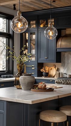 a kitchen island with stools and lights hanging from it's ceiling over it