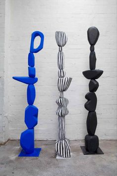 three different colored sculptures are standing next to each other in front of a white brick wall