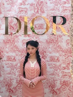 a woman standing in front of a wall with the word dior written on it